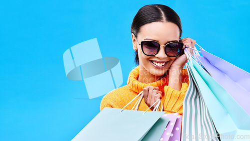 Image of Shopping gift bags, studio and woman portrait with a smile and happiness from boutique sale. Happy, customer and female model with store bag and sales choice in isolated blue background with mockup