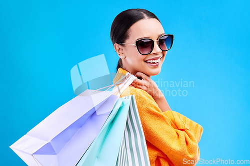 Image of Shopping bags, studio and woman portrait with deal and happiness from boutique sale. Happy, customer and wealthy female model with store bag and sales choice in isolated blue background with person