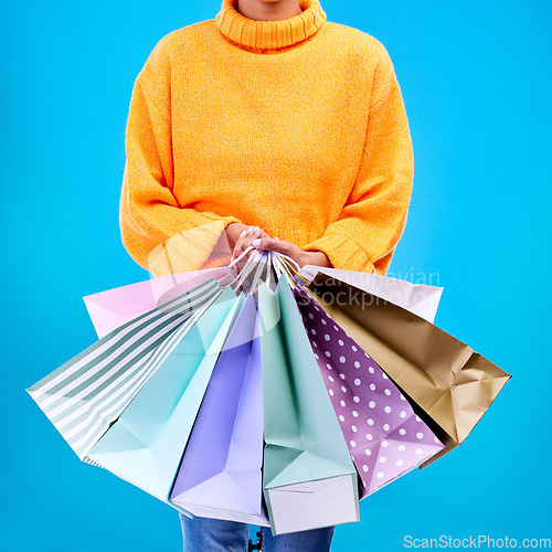 Image of Woman, hands and shopping bags for purchase, sale or luxury accessories against a blue studio background. Hand of female shopper holding gift bag, buy or discount presents of retail products or items