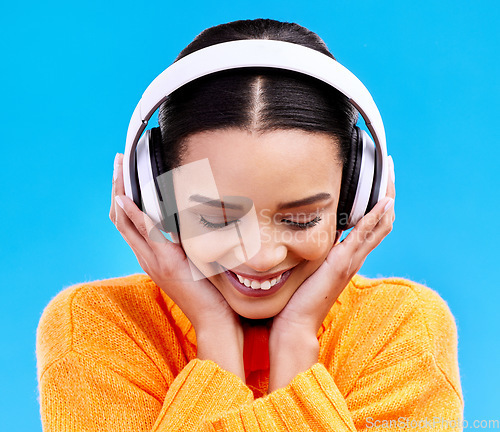 Image of Music headphones, woman and smile on blue background, studio and color backdrop. Happy female model listening to sound, streaming album and audio connection on media, gen z and hearing radio podcast