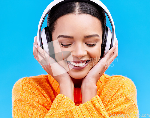 Image of Headphones, happy music and woman in studio, blue background and backdrop. Smile, female model and listening to radio, streaming album and excited audio connection, sound and subscription to podcast