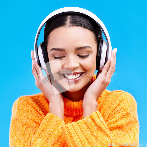 Image of Headphones, happy woman and listening to music on blue background, studio and color backdrop. Gen z female model streaming audio, album and media connection to radio, sound and subscription podcast