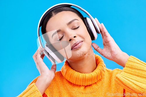 Image of Headphones, calm music and woman in studio, blue background and backdrop. Peace, female model and listening to music, relax and streaming album on audio connection, sound or hearing zen radio podcast