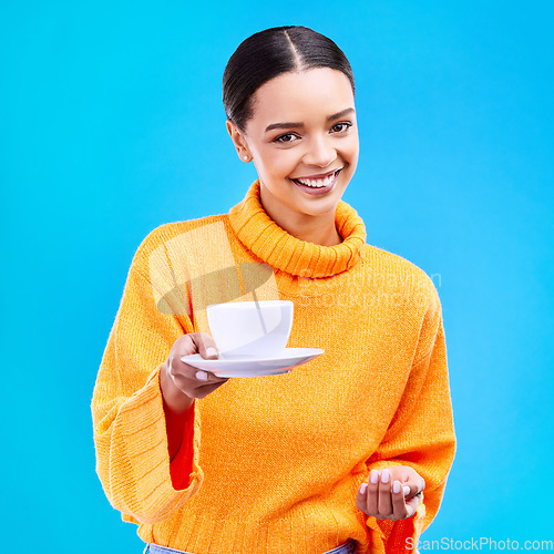 Image of Woman, portrait and smile with coffee in studio for happiness for cafe advertising and mockup. Face of a happy female model giving tea cup on a blue background in hand for motivation and hospitality