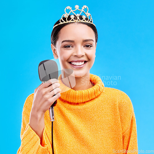 Image of Woman, crown and microphone in studio portrait with smile for singing, recording or performance by blue background. Happy singer, girl and model with mic for speech, announcement or talk with tiara