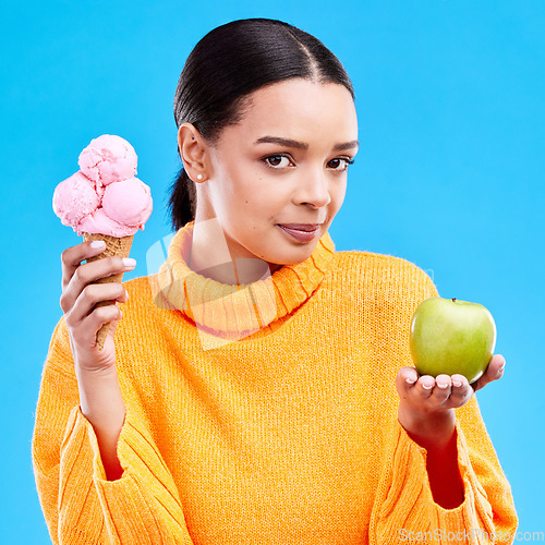 Image of Woman, ice cream and apple with choice in portrait for health, wellness and diet by blue background. Girl, model and decision for healthy fruits, junk food and balance in nutrition for body benefits