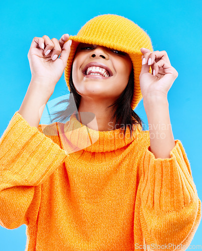 Image of Fashion, happy and cover with woman and beanie in studio for hiding, winter and goofy. Playful, happiness and smile with female and knitted hat isolated on blue background for funny, silly and cool