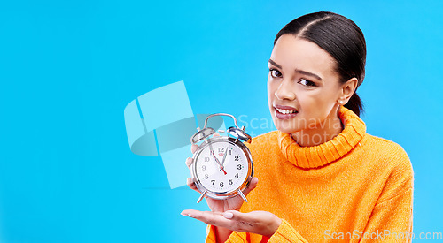 Image of Woman, alarm clock and annoyed in studio portrait with mockup space by blue background. Gen z girl, student and model with watch for time management, schedule or angry face in mock up by backdrop