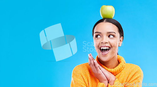 Image of Wow, apple on head and a woman in studio on a blue background for product placement on mockup. Surprise, balance and space with an attractive young female posing to promote health, diet or nutrition