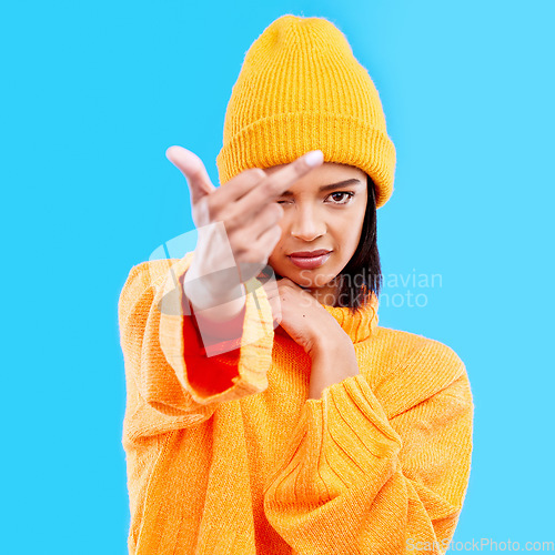 Image of Portrait, hand gesture and rude with a woman on a blue background in studio wearing a yellow beanie or outfit. Emoji, angry and insult with an attractive young female showing the middle finger