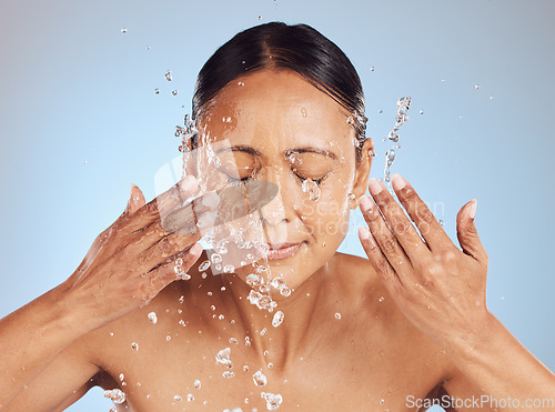 Image of Senior woman, cleaning face and water drops, beauty and sustainable skincare, antiaging on blue background. Facial, healthy skin and eco friendly dermatology, natural cosmetics and female in studio