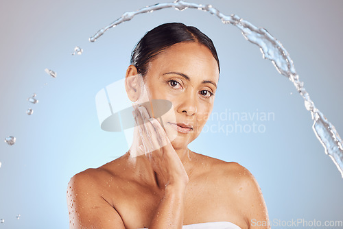 Image of Elderly woman, water splash and beauty portrait, hygiene and sustainable skincare for antiaging on blue background. Shower, clean serious female and eco friendly dermatology, cosmetic care in studio