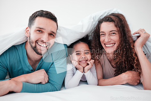 Image of Family in bed, happy parents and child in portrait, relax and smile together with love and care. Spending quality time under blanket, bonding and relationship, man and woman with young girl at home