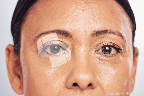 Image of Closeup, portrait and eyes of a mature woman isolated on a studio background for skincare beauty. Wrinkles, treatment and the face of a model for anti aging, facial wellness and care for skin