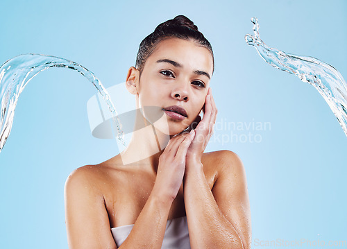 Image of Water splash, portrait and woman shower in studio, blue background and healthy beauty of natural skincare. Serious female model, wet and cleaning for hygiene, hydration and wellness on color backdrop