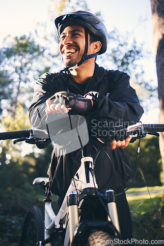 Image of Forest, fitness and smile, cyclist on bicycle in nature with helmet, exercise adventure trail and healthy mindset. Cycling, relax and man with mountain bike in trees for workout, motivation or energy