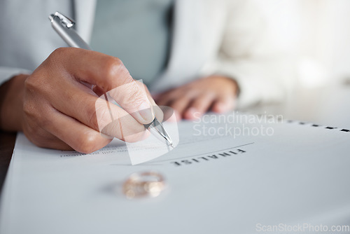 Image of Signature, ring and divorce paper of a woman at table with legal paperwork, anxiety or documents. Female person sign with pen on papers with wedding band jewellery for separation, cheating or mistake