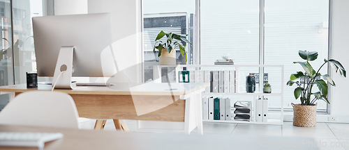 Image of Empty office, interior and computer on desk in workplace, company or workspace. Room, desktop and table with corporate furniture, plants and window with modern design for business with nobody.