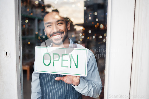 Image of Asian man, small business and portrait with open sign on window for service in coffee shop or restaurant. Happy male entrepreneur holding billboard, poster or welcome for opening retail store or cafe