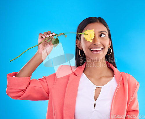 Image of Rose, love and valentines day with a woman on a blue background in studio thinking about romance. Spring, gift and yellow flower with an attractive young female holding a plant for summer or growth