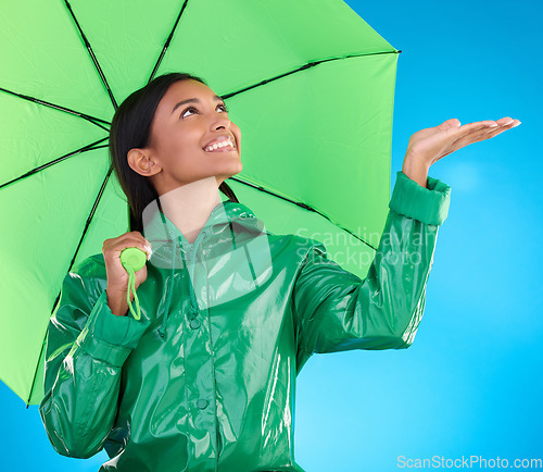 Image of Happy, winter and a woman with an umbrella for the rain isolated on a blue background. Smile, insurance and a girl feeling for drops of water, bad weather and drizzling with shelter on a backdrop