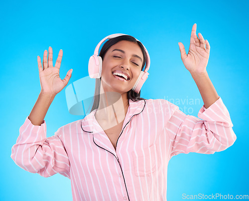 Image of Smile, dance and woman in pajamas, headphones and inspiration against a blue studio background. Female, happy and lady with headset, waking up and dancing for motivation, wellness and streaming music