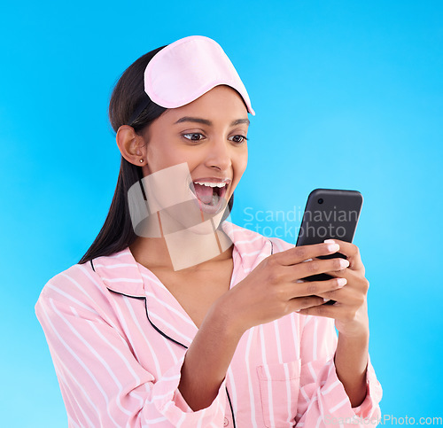 Image of Pajamas, shocked and woman surprised at her phone due to good news notification isolated in a studio blue background. Excited, cellphone and female with wow expression for a discount or sale