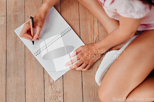 Image of Notebook, writing and planning woman hands with journal ideas, inspiration or creativity on wood floor above. Creative person closeup in mindfulness, healing notes and self care book for writer goals