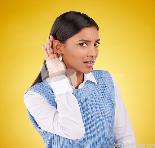 Image of Portrait, confused and gossip with a woman on a yellow background in studio listening to a secret. Hand gesture, doubt and shock with an attractive young female cupping her ear to hear a rumor