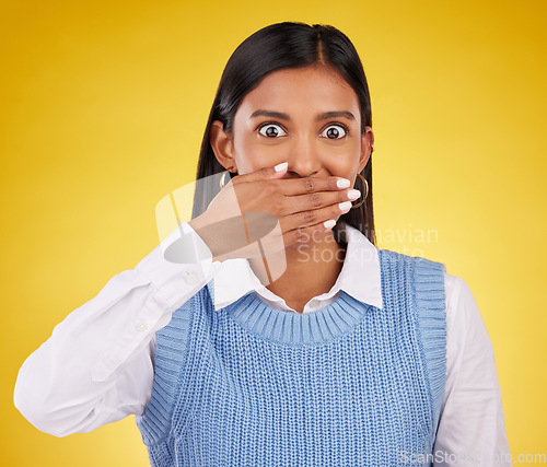 Image of Portrait, wow and gossip with a woman on a yellow background in studio looking surprised by an announcement. Face, shock and news with an attractive young female standing hand over mouth in awe