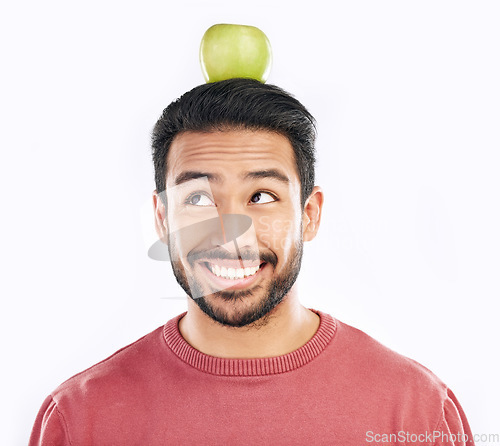Image of Happy, apple and balance on a head with a man in studio isolated on a white background for diet or nutrition. Smile, nutritionist and food with a healthy young male balancing fruit for detox or fiber