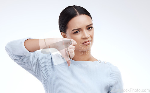 Image of Thumbs down, woman and portrait with no opinion and choice in a studio. Isolated, white background and bad review of a young female feeling disappointed from voting and emoji of fail hand sign