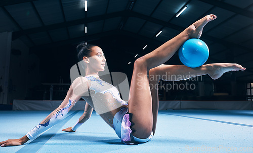 Image of Woman, gymnastics and ball between legs of performance, competition training or dancing in dark sports arena. Female athlete, rhythmic movement and creative talent in solo concert, agility or balance