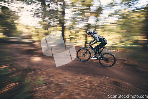Image of Bicycle, mountain bike and man cycling in the forest or woods fast, speed and adrenaline with motion blur. Extreme sports, actions and rider cycling for exercise, fitness and workout in nature