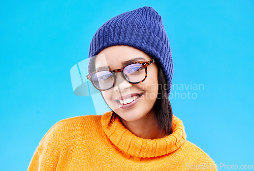 Image of Portrait of woman in winter fashion with smile, beanie and glasses isolated on blue background. Style, happiness and gen z girl in studio backdrop with happy face and warm clothing for cold weather.