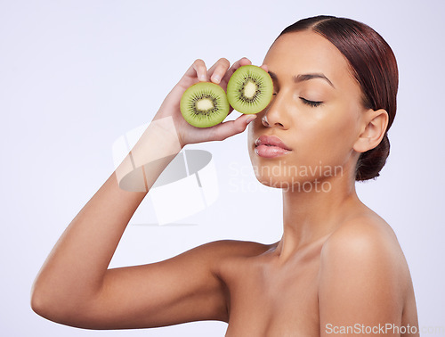 Image of Beauty, skincare and kiwi with woman in studio for natural cosmetics, diet and nutrition. Product, glow and self care with female model and fruit on white background for spa, food and vitamin