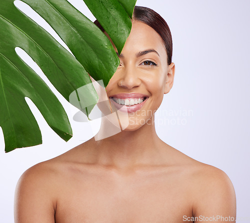 Image of Portrait, leaf and woman in studio for skincare, dermatology and cosmetic on purple background. Beauty, face and girl model relax, smile and happy with glowing skin, cosmetology or monstera treatment