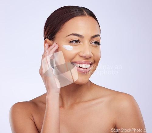 Image of Woman, skincare cream and smile in studio for self care, thinking or beauty with product application on face. Girl, model and facial skin wellness with cosmetics, health and dermatology by background