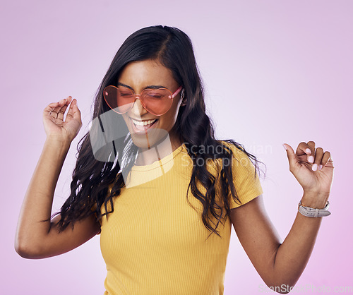 Image of Dancing, sunglasses and cool woman excited, happy and confident isolated in a pink studio background with joy. Singing, music and young genz female dance in celebration of a party energy with glasses