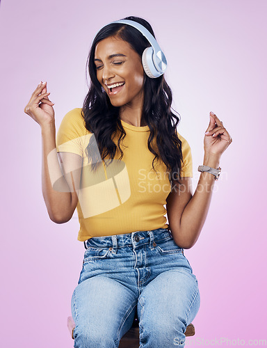 Image of Music, headphones and Indian woman dance on pink background listening to track, audio and radio. Relax, happy and isolated girl singing streaming song for dancing, chilling and happiness in studio