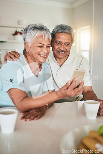 Image of Phone, video call and elderly couple in a kitchen happy, smile and embrace in their home. Smartphone, love and old people pose for selfie, photo or profile picture while enjoying retirement together