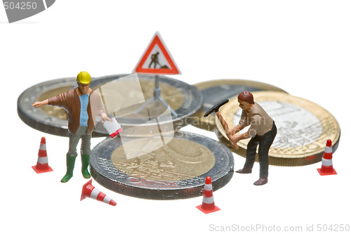 Image of Miniature figures working on a heap of Euro coins.