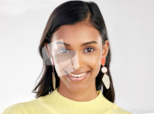 Image of Portrait, fashion and beauty with a woman on a white background in studio wearing earrings or accessories. Face, smile and happy with an attractive young indian female closeup for contemporary style