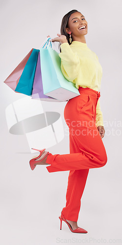 Image of Portrait, retail and sale with a woman customer in studio on a gray background for shopping or consumerism. Fashion, luxury or happy with a female consumer or shopper carrying bags on her shoulder