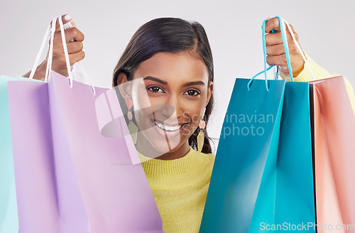 Image of Portrait, shopping and smile with a woman customer in studio on a gray background for retail or consumerism. Fashion, luxury and happy with a female consumer or shopper showing bags of bargains