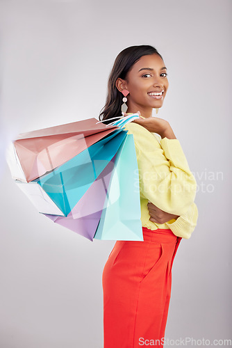 Image of Portrait, shopping and sales with a woman customer in studio on a gray background for retail or consumerism. Fashion, luxury or smile with an attractive young female carrying bags over her shoulder