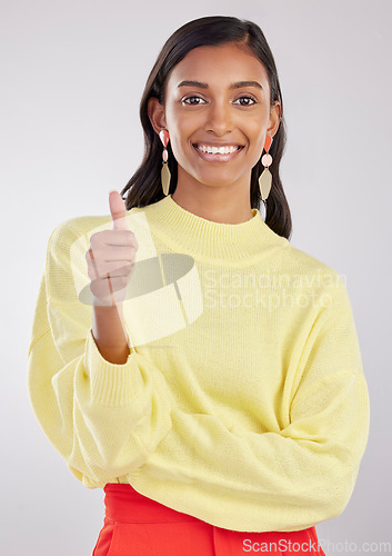 Image of Portrait, thumbs up and fashion with a woman in on a gray background studio to promote contemporary clothes. Thank you emoji, motivation and style with an attractive female indoor to model clothing