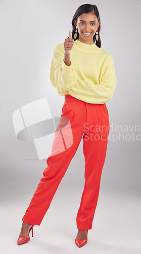 Image of Portrait, thumbs up and fashion with a woman in studio on a gray background to promote contemporary clothes. Thank you, motivation and style with an attractive female indoor to model trendy clothing