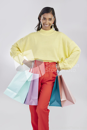 Image of Portrait, shopping and sale with a woman customer in studio on a gray background for retail or consumerism. Fashion, luxury or bags with a female consumer or shopper standing hands on hips for deals