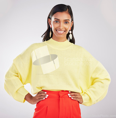 Image of Happy woman, portrait smile and confidence standing isolated with hands on hips against a gray studio background. Face of stylish and confident Indian female posing and smiling in colorful fashion